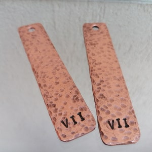 May include: Two hammered copper tags with Roman numeral engravings. The tag on the left says "VII" and the tag on the right says "VII".