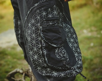 May include: Black cargo pants with a white geometric pattern and a large pocket on the side. The pants have a belt with metal buckles.
