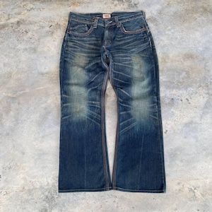 May include: Blue denim jeans with a faded wash and flared legs. The jeans have red stitching along the seams and pockets. The waistline features a small red and white tag.