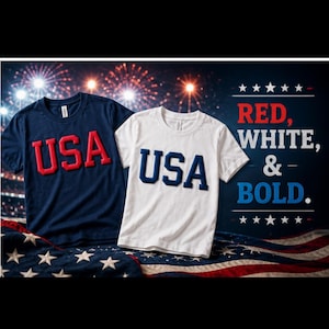 May include: A navy blue t-shirt with red puff-print text reading USA and a white t-shirt with navy blue puff-print text reading USA. The text RED, WHITE, & BOLD is printed on the right side with stars above and below the lettering.