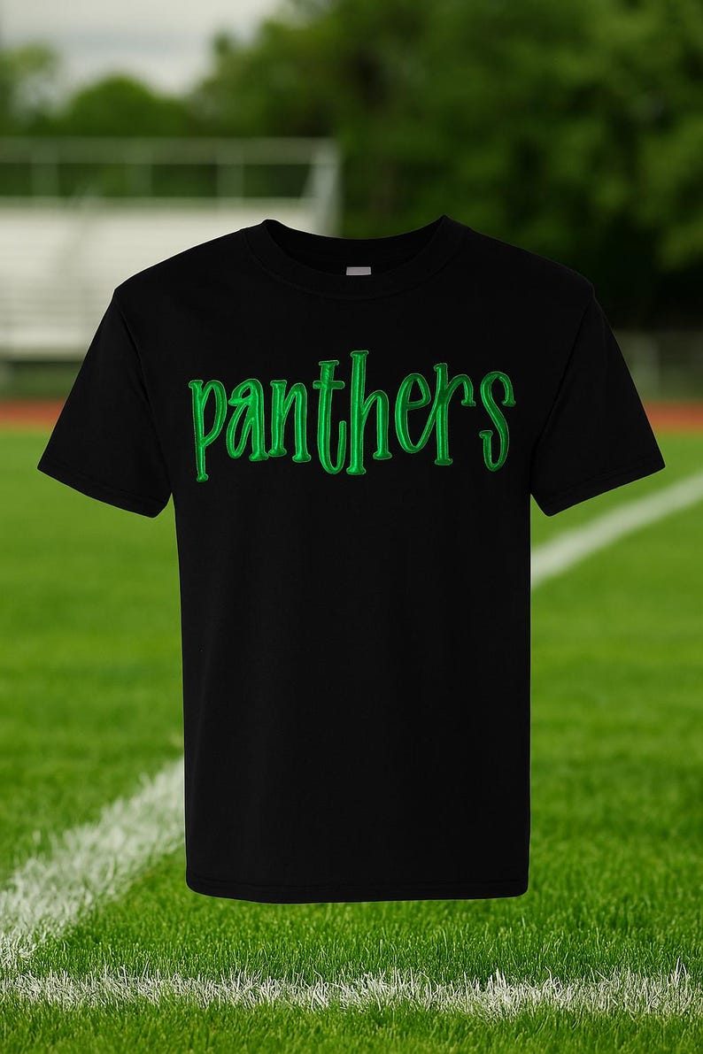 May include: A black short-sleeved t-shirt featuring the word "panthers" printed across the chest in a bright green, stylized font with a subtle shadow effect. The garment has a classic crew neckline and a straight hemline design.