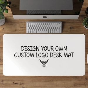 May include: A white desk mat with the text "DESIGN YOUR OWN CUSTOM LOGO DESK MAT" in black, along with a stylized bird graphic. The mat is on a wooden desk, with a keyboard, mouse, and computer monitor visible.