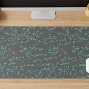May include: A rectangular desk mat featuring a dark gray background with a repeating pattern of light teal chemical formulas, molecular structures, and mathematical equations printed across the entire surface of the mat.