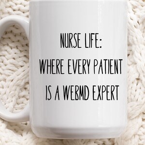 May include: White ceramic coffee mug with black text that reads "Nurse Life: Where every patient is a WebMD expert."