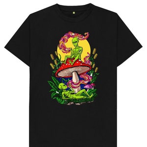 May include: Black t-shirt featuring a graphic of two green aliens sitting on a red and white mushroom. The aliens are smoking and the mushroom is surrounded by green leaves and yellow flowers.