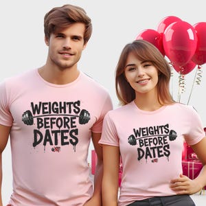 May include: Two people wearing matching pink t-shirts with the text "WEIGHTS BEFORE DATES" in black. The design includes a barbell and dripping paint effect. The shirts are short-sleeved.