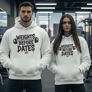 May include: Two white hoodies with the text "WEIGHTS BEFORE DATES" in black and gray. The hoodies have a front pocket and a drawstring hood. The background is a gym setting with weights and exercise equipment.