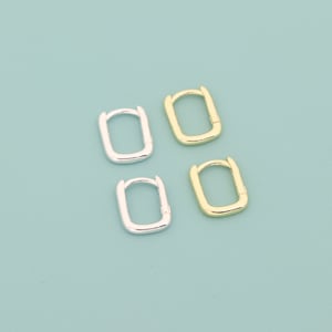 May include: Two pairs of hoop earrings, one pair is gold and the other is silver. The earrings are rectangular in shape.