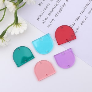May include: Five half-circle shaped resin cabochons in different colours: red, turquoise, green, pink, and purple. The cabochons have two holes at the top.