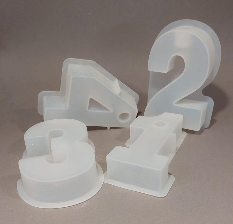 Könnte beinhalten: Vier durchscheinende Silikonformen mit den Zahlen 1, 2, 3 und 4. Jede Form hat eine andere Form und Größe mit abgerundeten Kanten. Die Formen sind für die Herstellung von Artikeln in Form von Zahlen konzipiert, wahrscheinlich zum Backen oder Basteln.