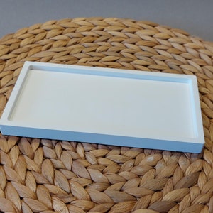 Könnte beinhalten: Ein weißes rechteckiges Tablett mit einer glatten Oberfläche. Das Tablett ist aus Keramik und hat einen leicht erhöhten Rand.