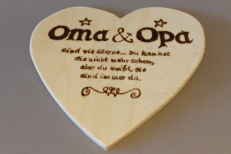Könnte beinhalten: Eine herzförmige Holzplakette mit einer eingebrannten Botschaft, die lautet: "Oma & Opa Sind wie Sterne... Du kannst Sie nicht mehr sehen, aber du weißt, sie sind immer da."