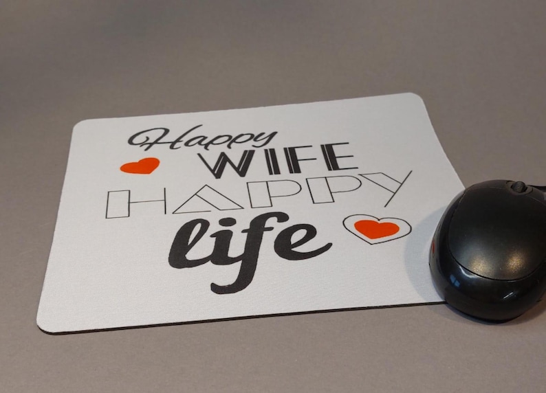 Könnte beinhalten: Eine weiße Mausmatte mit dem Text "Happy Wife Happy Life" in Schwarz mit zwei roten Herzen.