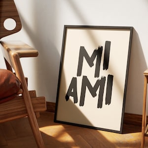 Peut inclure: Une impression encadr&eacute;e noire avec le texte "MI AMI" en caract&egrave;res gras blancs sur un fond cr&egrave;me.