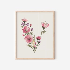 May include: A framed watercolour print of pink and purple flowers with green foliage on a cream background. The artwork is presented in a light wood frame, offering a delicate and elegant appearance. Ideal for home decoration, this piece is a lovely addition.