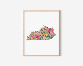 Könnte beinhalten: Ein gerahmter Aquarelldruck mit der Umrissform von Kentucky, gefüllt mit bunten Blumen und Blättern. Das Kunstwerk zeigt rosa, orange und grüne Farbtöne und erzeugt eine lebendige Ästhetik. Der Druck ist vor einem weißen Hintergrund.