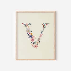 May include: A framed watercolour print of the letter "V", formed from an arrangement of colourful flowers and leaves. The artwork displays pink, purple, blue, and yellow blooms against a cream backdrop. The wooden frame provides a natural aesthetic.