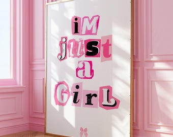 May include: A white poster with a pink and black text overlay that reads "i'm just a girl". The poster is framed in gold and is hanging on a pink wall.