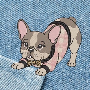 May include: Embroidered patch of a French Bulldog in a playful pose. The dog has a grey and white coat, pink ears, and is wearing a pink and black sweater with a bow tie. The patch is on a blue denim background.