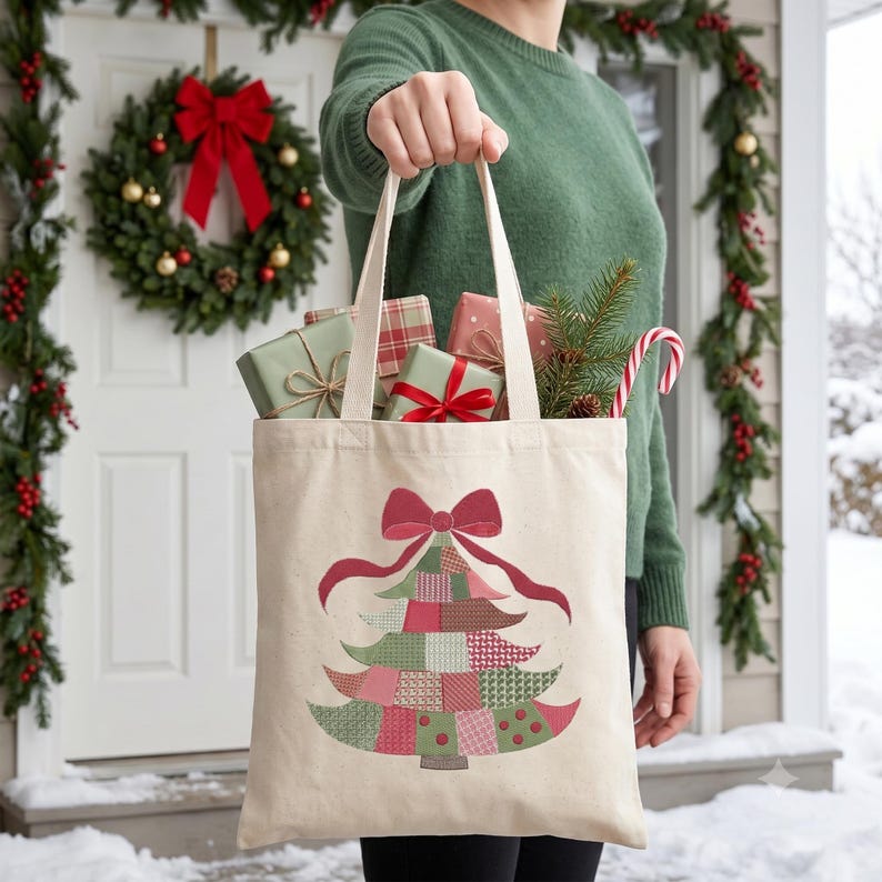 May include: A beige canvas tote bag featuring a printed graphic of a stylized Christmas tree made of various red, green, and white patterned patches, topped with a large red bow. The bag is filled with wrapped gift boxes and pine branches.