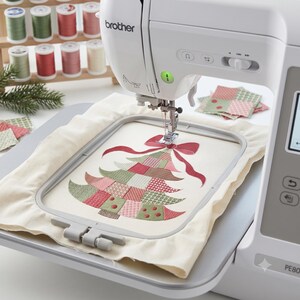May include: A white Brother PE800 embroidery machine with a rectangular hoop holding cream fabric. The fabric features a stitched Christmas tree design made of patchwork-style squares in red, green, and pink, topped with a red bow.