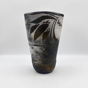 May include: A black and white ceramic vase with a stylized floral design. The vase has a rounded bottom and a flared opening.