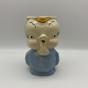 May include: A vintage ceramic owl figurine with a light blue body and a cream-colored head. The owl has black eyes, a gold beak, and gold accents on the head. The figurine is a decorative item.
