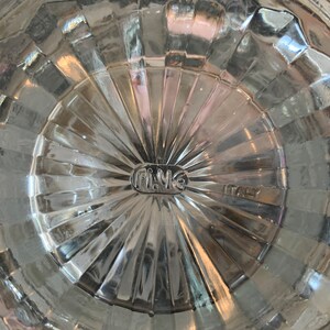 May include: Close-up of the bottom of a clear glass pitcher with a textured surface. The bottom of the pitcher has a circular label that reads "Fi.Me" and "ITALY".