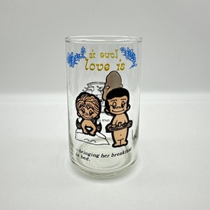 May include: A clear glass with a black and white illustration of a couple. The text on the glass reads "Love is... bringing her breakfast in bed."