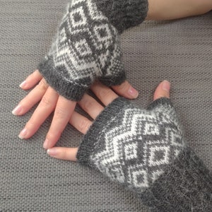 May include: A pair of grey and white fingerless gloves with a geometric pattern. The gloves are made of a soft, fuzzy material.