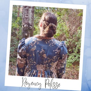 Puede incluir: Una pelisse de estilo Regencia de estampado floral azul y marrón con cuello alto y mangas abullonadas. La pelisse la lleva puesta una persona de espaldas a la cámara. La persona lleva el pelo recogido en un moño con una pinza decorativa.