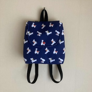 May include: A navy blue backpack featuring a repeating pattern of white llamas with orange and yellow saddle blankets. The bag includes a top flap closure, a black fabric handle at the top, and two adjustable black fabric shoulder straps.