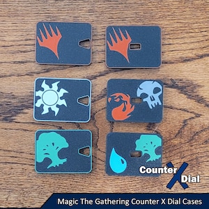 Puede incluir: Seis diales de contador cuadrados negros Magic: The Gathering con diferentes símbolos y colores. Los símbolos incluyen un símbolo de maná, una calavera, un árbol, una gota de agua y dos versiones diferentes del mismo símbolo. El texto "Counter Dial" es visible en la esquina inferior derecha de la imagen.