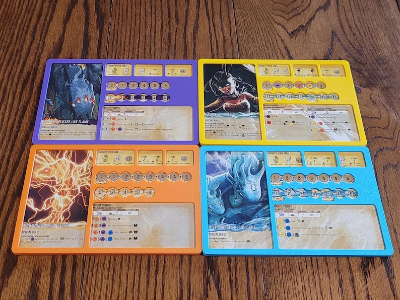 May include: Four colorful game boards with illustrations and text. The boards are purple, yellow, orange, and blue. Each board has a different image and a series of icons and text boxes. The boards appear to be for a tabletop game.