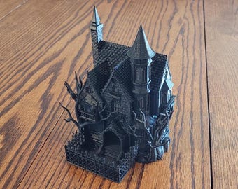 May include: A black 3D printed haunted house with a tall tower, a fence, and a tree. The house has a detailed design with windows, a door, and a roof.