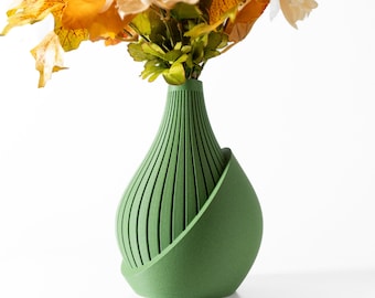 May include: A green ceramic vase with a unique, modern design. The vase has a rounded base and a tall, slender neck with vertical lines. It is perfect for displaying a bouquet of flowers.