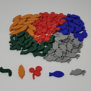 May include: A collection of colorful game pieces in various shapes, including leaves, berries, fish, and mice. The pieces are made of plastic and are in shades of green, orange, red, blue, and gray.