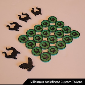 Puede incluir: Un conjunto de 25 fichas de juego personalizadas verdes y negras con una silueta negra de un par de cuernos. Las fichas están dispuestas en una cuadrícula. También hay cinco fichas de plástico negro con forma de cuernos.