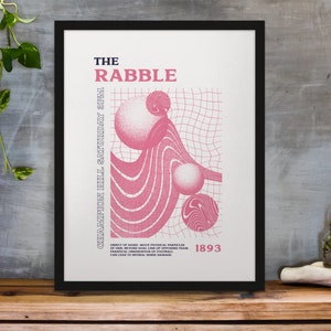 Op de afbeelding: Ingelijste kunstdruk met een zwarte rand. De print toont de tekst "THE RABBLE" in roze, abstracte roze vormen en de tekst "CHAMPION HILL SATURDAY 3PM" en "1893". De achtergrond is gebroken wit.