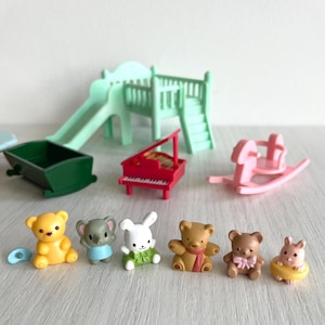 May include: A set of seven miniature animal figurines, including a yellow bear, a grey elephant, a white rabbit, three brown bears, and a brown hamster. The figurines are arranged in a row on a light wood surface.