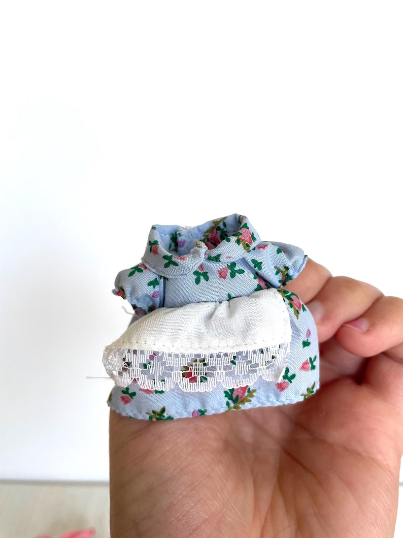 May include: A light blue dress with a floral print and white lace trim. The dress is made of a soft, lightweight fabric and has a simple, classic design.