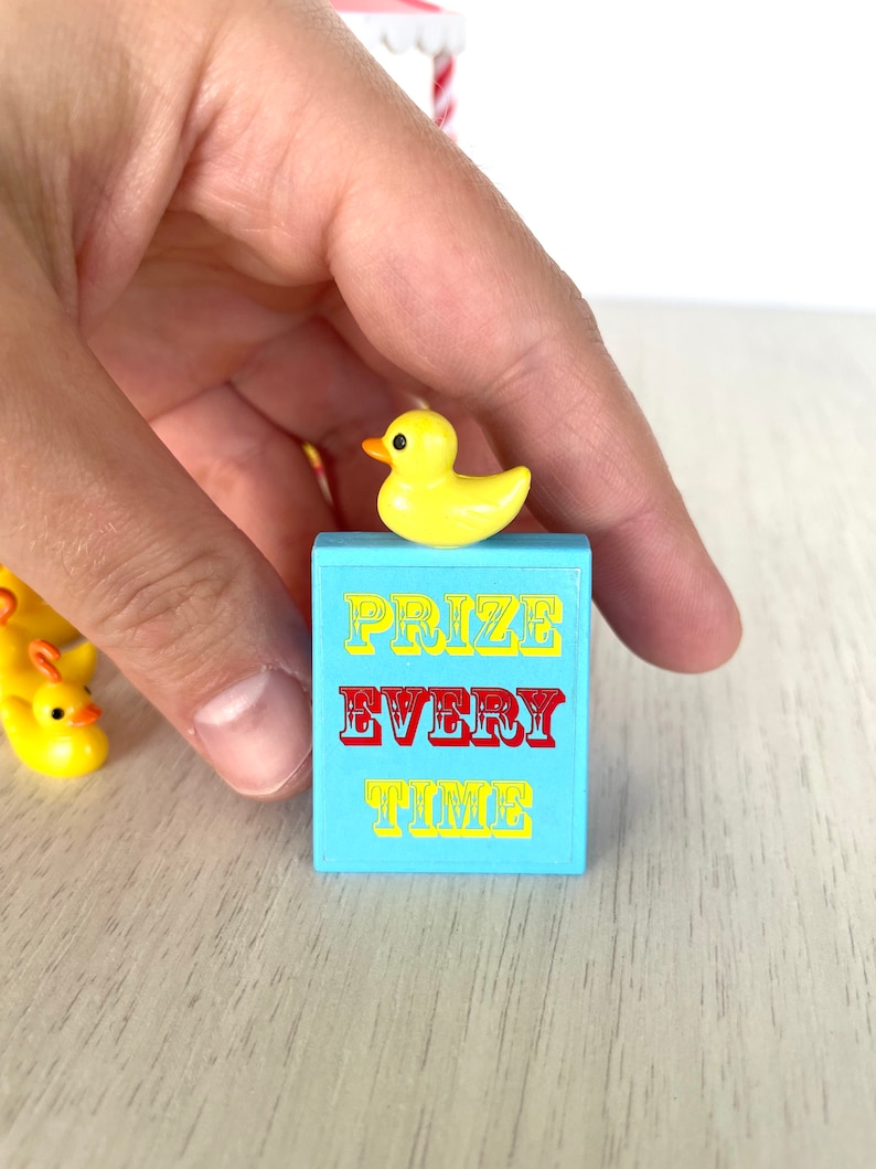 Op de afbeelding: Een blauw en geel bord met de tekst "PRIZE EVERY TIME" en een gele rubberen eend erop.