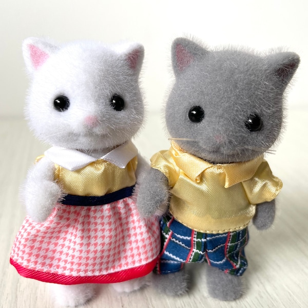 Pareja de gatos persas de Calico Critters, con atuendos amarillos a juego y figuras de gatitos grises y blancos.