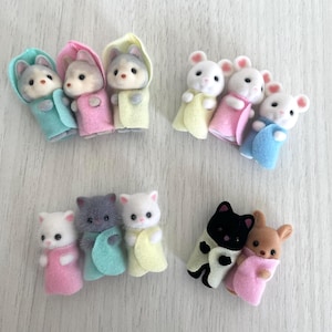 以下が含まれることがあります： フード付きタオルをつけたぬいぐるみ動物のフィギュア9個セット。動物は、灰色のオオカミ、白いマウス、灰色の猫、黒い猫、茶色の鹿。タオルの色は、ピンク、ブルー、イエロー、グリーンなどがあります。