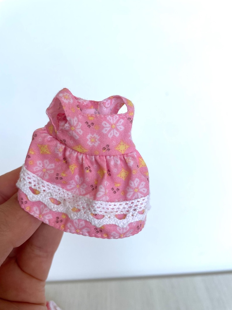 May include: A pink sleeveless dress with a white lace trim and a floral pattern.