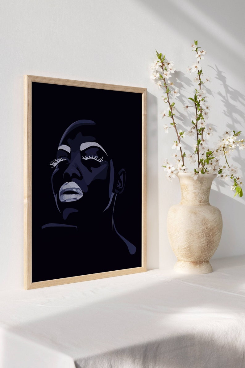 May include: A framed black and white illustration of a woman's face with closed eyes and dramatic makeup. The woman's face is in profile and her lips are slightly parted. The background is black.