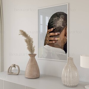 May include: A framed print of a black and white illustration of a person with their hand on the back of their head. The print is in a white frame and is hanging on a white wall.