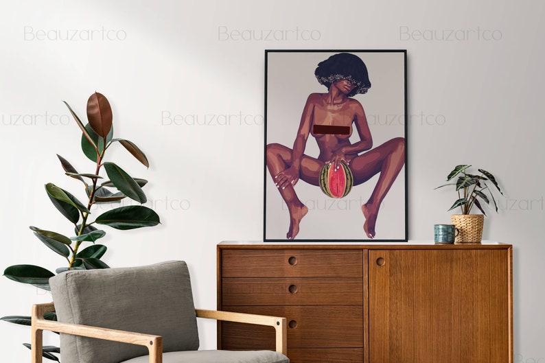 May include: A framed illustration of a woman with an afro hairstyle holding a watermelon. The woman is nude and sitting with her legs spread. The background is a light gray color.