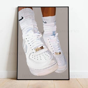 May include: A framed art print featuring a pair of white sneakers with gold accents and white socks. The sneakers have a classic design with laces and a textured sole. The socks have a black Nike logo.