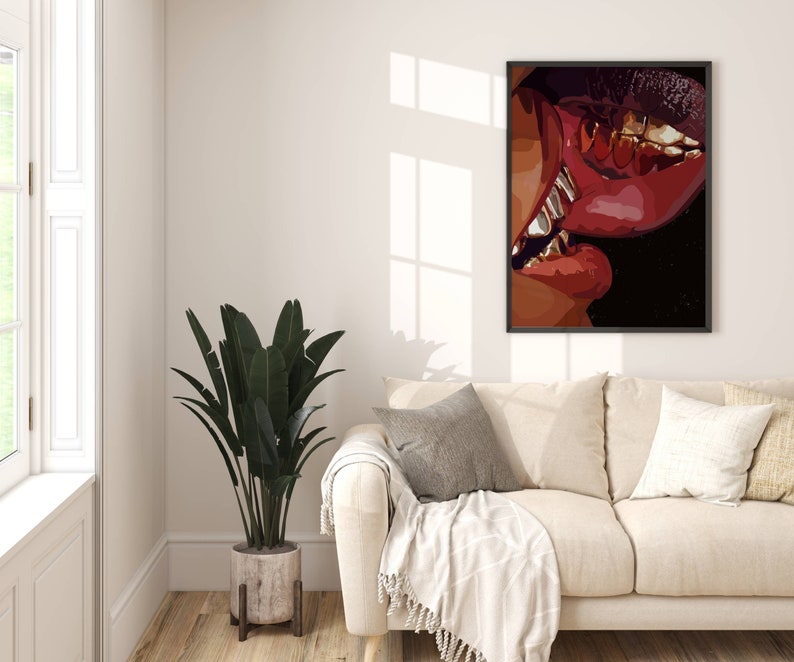 May include: A framed art print featuring a close-up of two sets of lips in shades of red and brown, with gold teeth visible. The artwork is displayed on a white wall above a beige sofa, with a large potted plant in the corner.